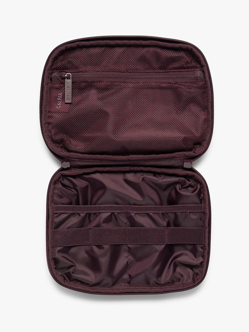Opened dark burgundy CALPAK Tech Organizer pouch with a top zipper, front zippered pocket, and a small silver metal brand zipper, shown against a plain white background