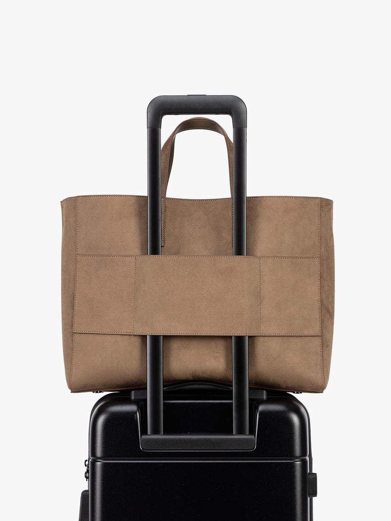 Backside laptop sleeve of a CALPAK Haven 16" Laptop Tote in Truffle Suede taupe brown tote bag with dual top handles and a matching adjustable shoulder strap, shown against a plain white background