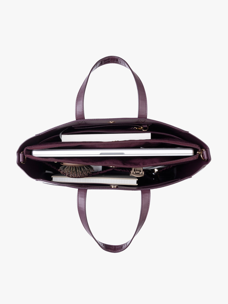 Items inside the CALPAK Haven 15" Laptop Tote in deep red Dark Cherry crocodile-embossed with dual top handles and a matching shoulder strap against a plain white background