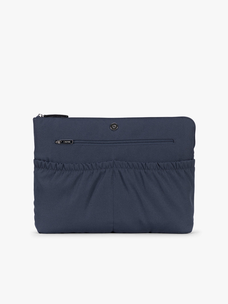 Laptop sleeve of a navy CALPAK Haven 15" Laptop Tote in Navy blue crocodile-embossed with dual top handles and a matching shoulder strap against a plain white background
