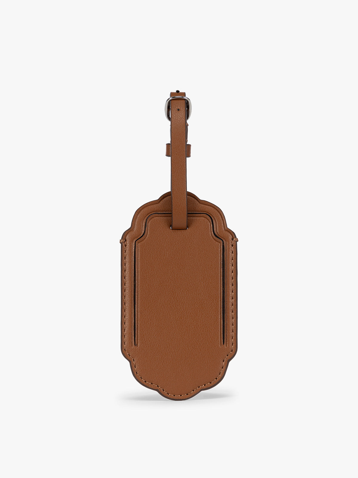 A honey brown CALPAK Vault luggage tag with a scalloped border and a matching honey brown strap, shown against a plain white background; ATV2601-HONEY-BROWN