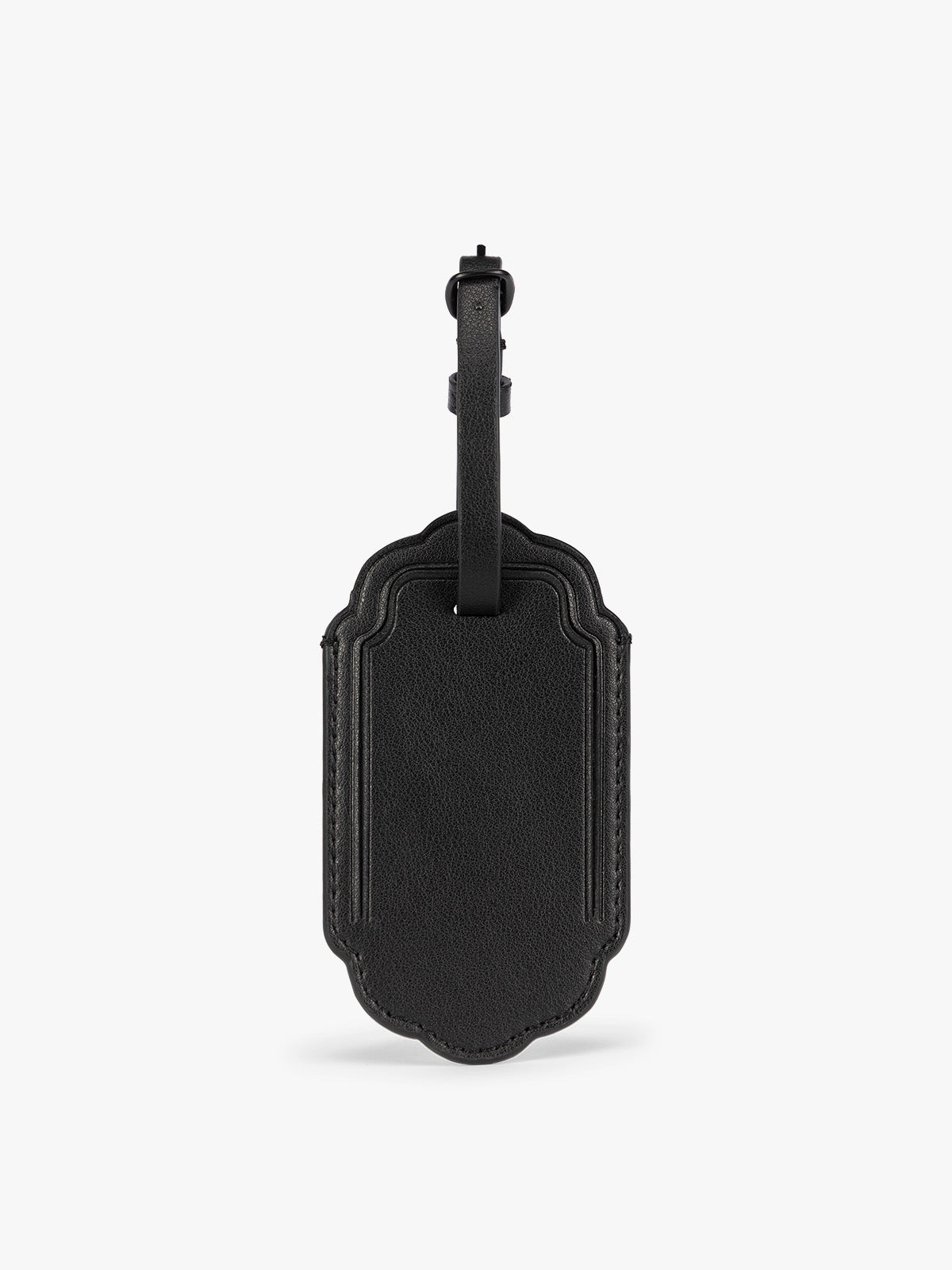 A black CALPAK Vault luggage tag with a scalloped border and a matching black strap, shown against a plain white background; ATV2601-BLACK