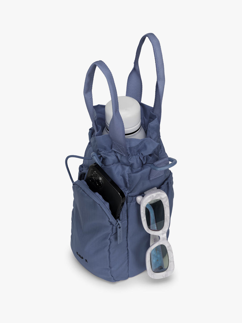 CALPAK Water Bottle Holder in dark blue Indigo with use of front phone pocket, side pocket with sunglasses and water bottle in main compartment