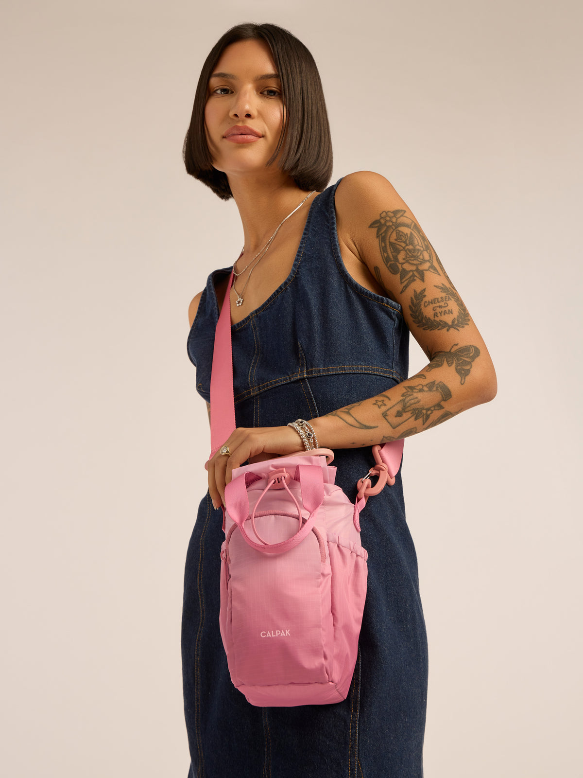Model wearing pink shoulder strap of CALPAK Water Bottle Holder in pink ombre Tea Rose; AWH2101-TEA-ROSE