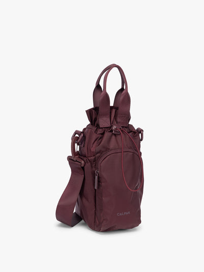 Dark burgundy CALPAK Water Bottle Holder with top handles, drawstring top, front zippered pocket, and a detachable shoulder strap; AWH2101-DARK-CHERRY view 1