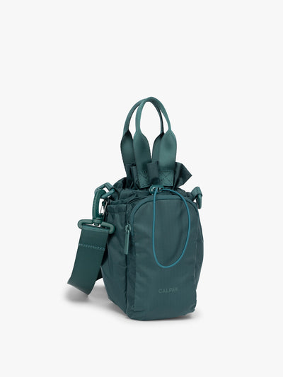 Dark green teal Kale CALPAK Water Bottle Holder with top handles, drawstring top, front zippered pocket, and a detachable shoulder strap; AWH2101-KALE view 1