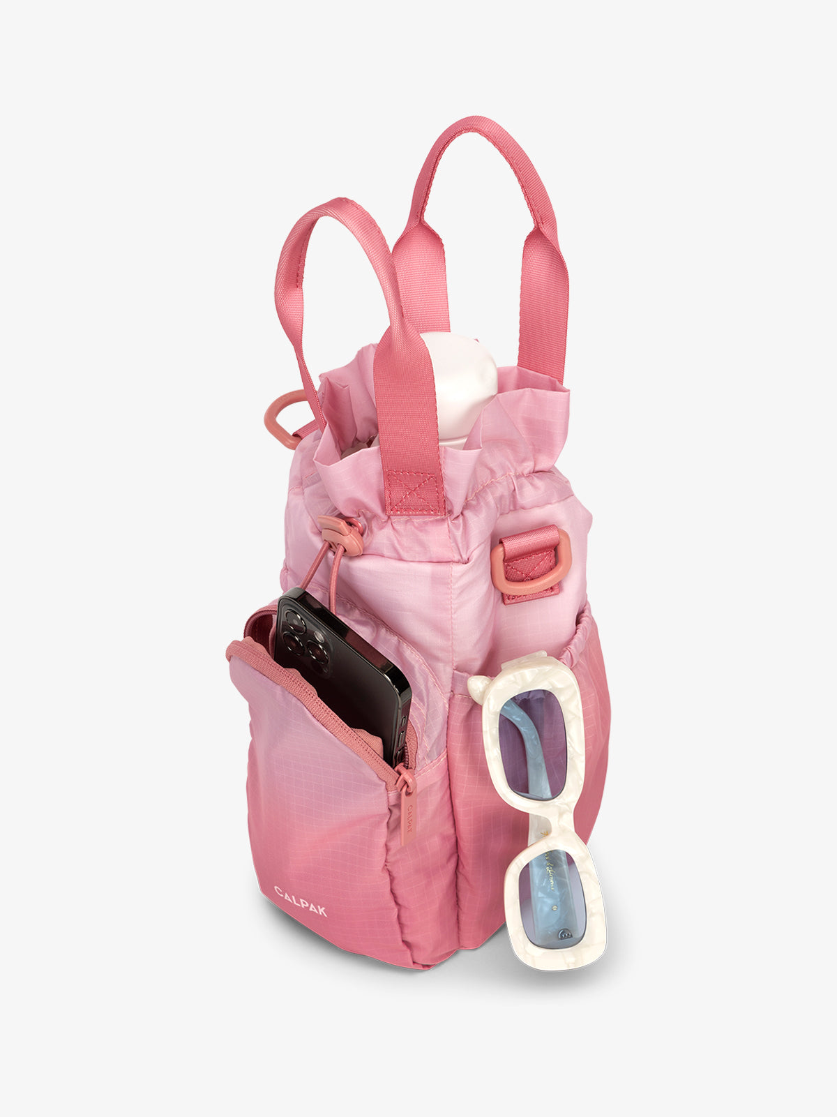 CALPAK Water Bottle Holder in pink ombre Tea Rose with use of front phone pocket, side pocket with sunglasses and water bottle in main compartment; AWH2101-TEA-ROSE