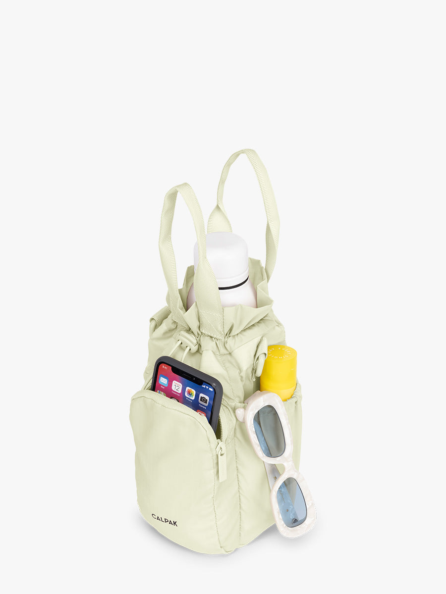 Water bottle and items inside the CALPAK Water Bottle Holder in light green Celadon; AWH2101-CELADON