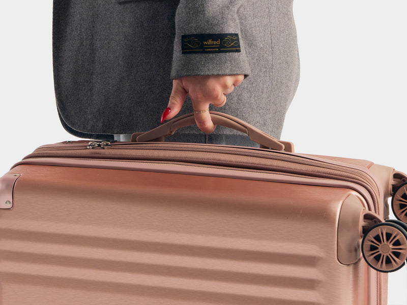 Model holding the CALPAK Ambeur Carry On Luggage in Rose Gold