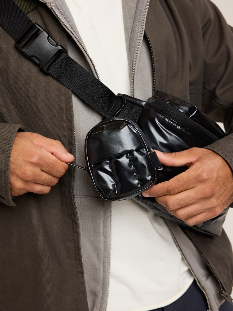 Model with CALPAK Luka Backpack Key Pouch in Glazed Black on a white background
