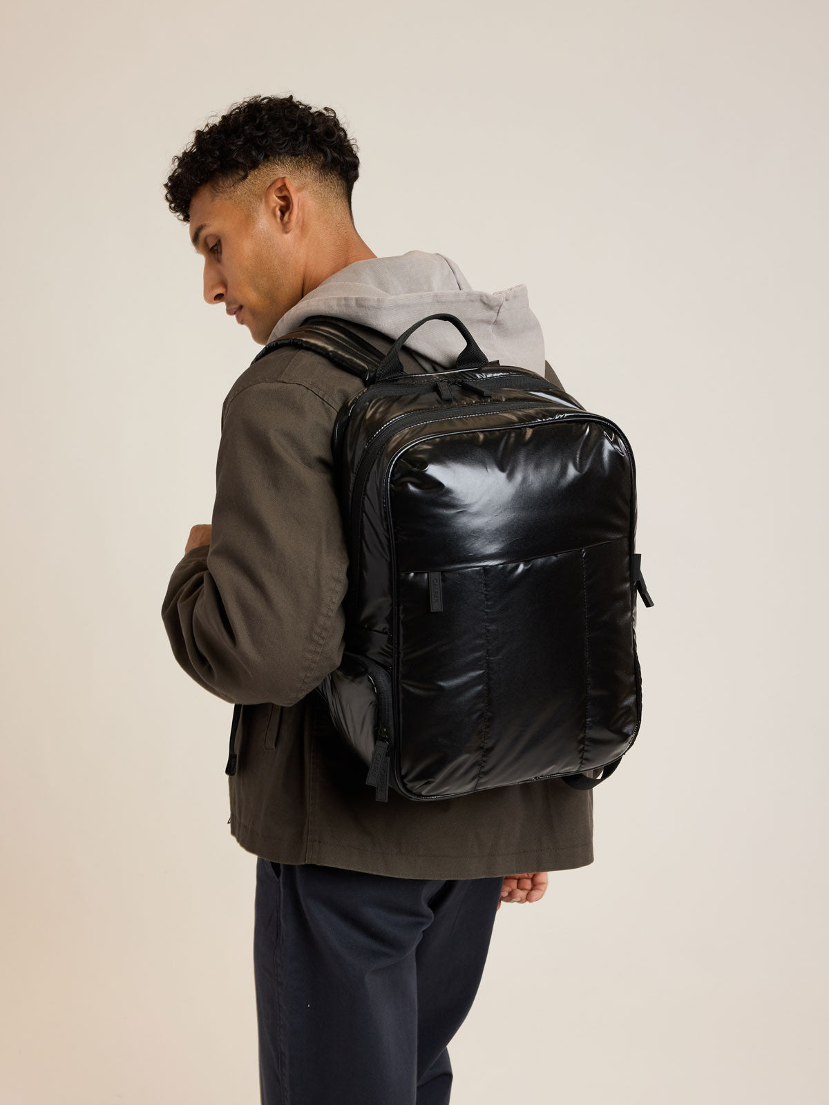 Model wearing CALPAK Luka Backpack in Glazed Black; BPL2001-GLAZED-BLACK