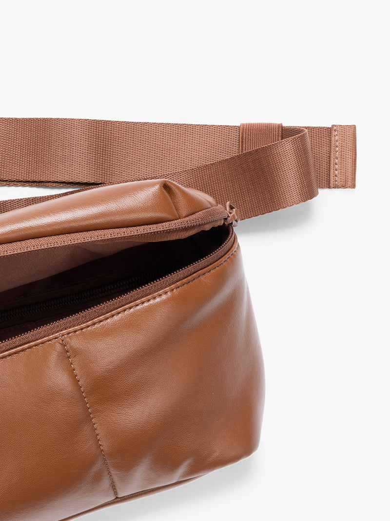 Closeup of front zippered pocket and crossbody strap of a light Honey Brown Mushroom vegan leather CALPAK Luka Belt Bag with a zippered front pocket and side straps, shown against a plain white background