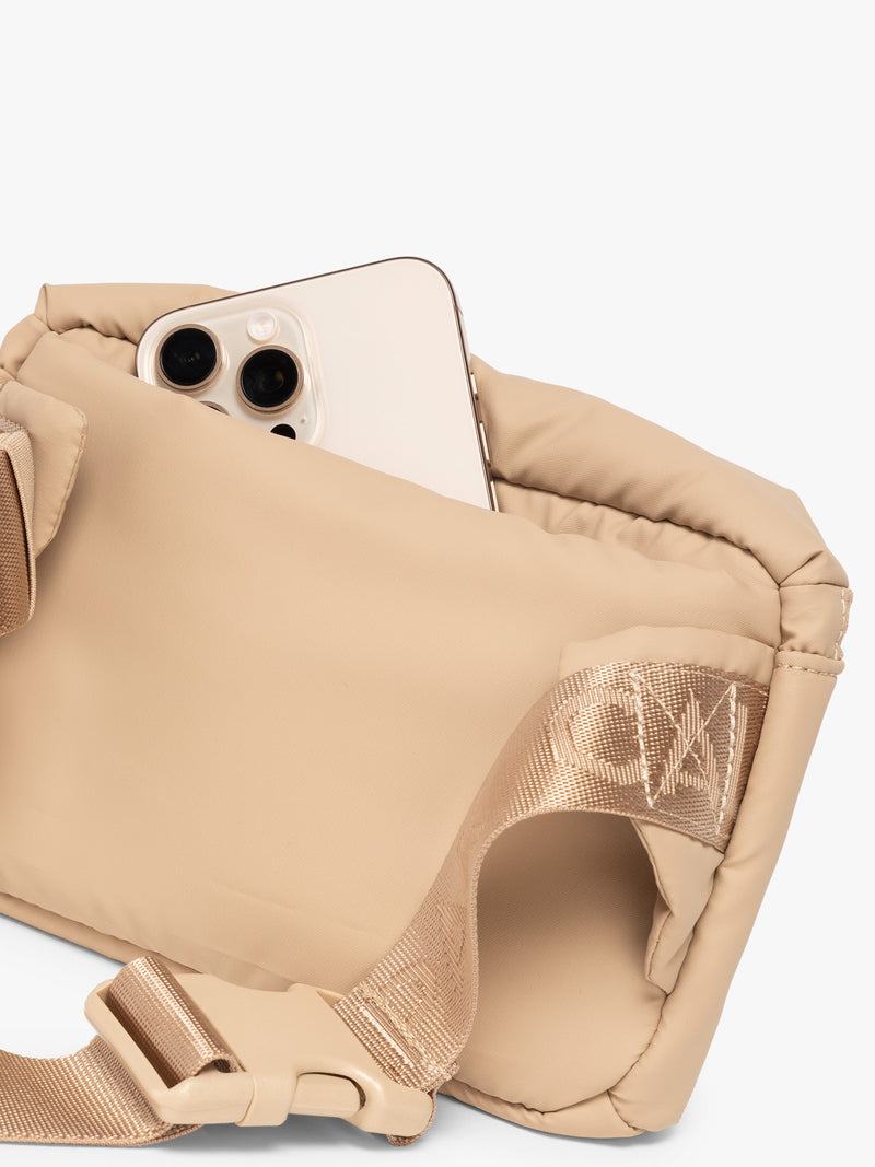 Phone in back pocket of CALPAK Luka Mini Belt Bag in beige Latte on white background