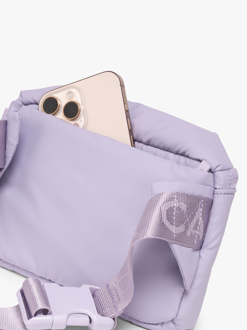Phone in back pocket of CALPAK Luka Mini Belt Bag in light purple Orchid on white background