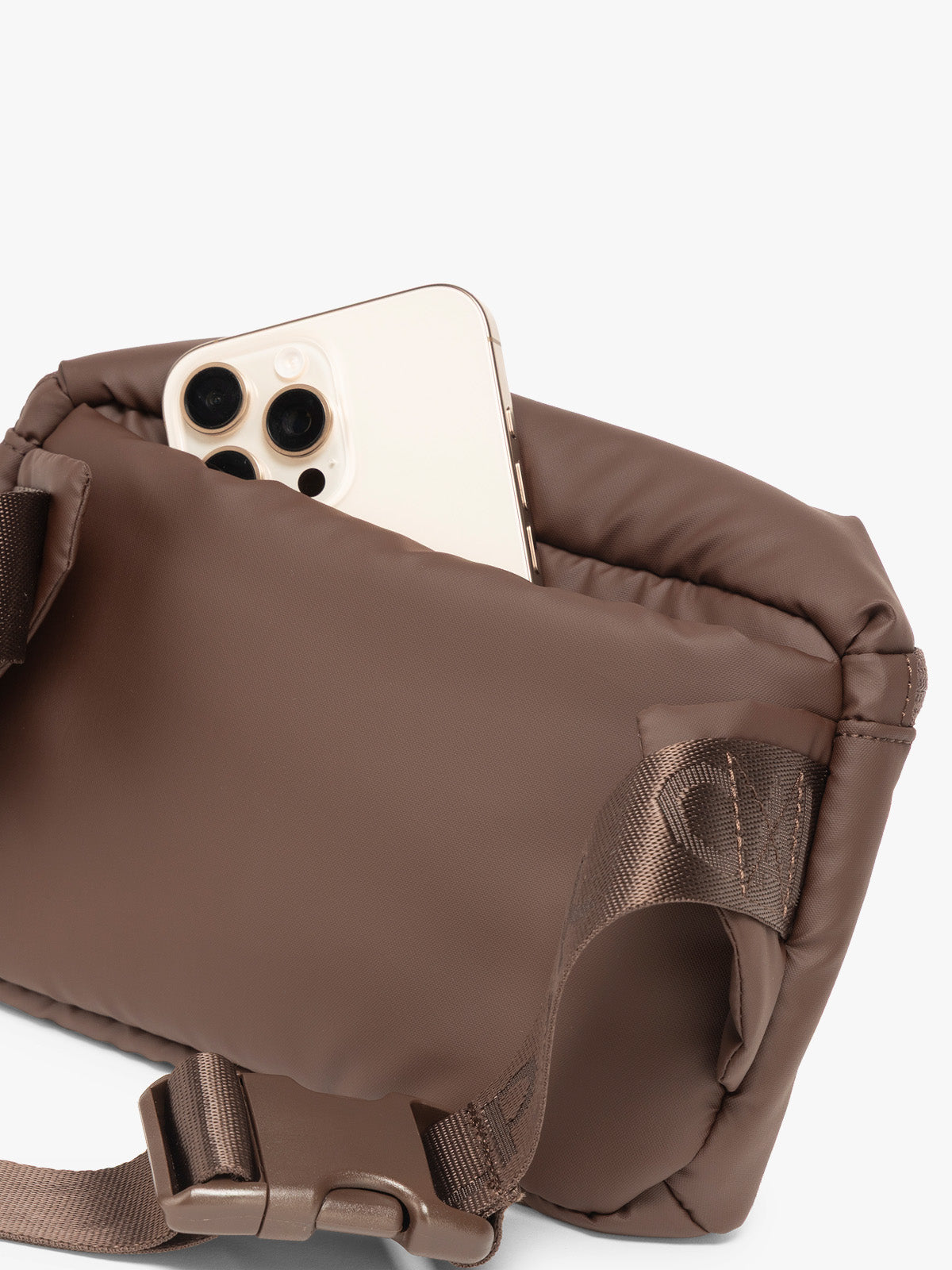 Phone in back pocket of CALPAK Luka Mini Belt Bag in brown Walnut on white background; BBM2201-WALNUT