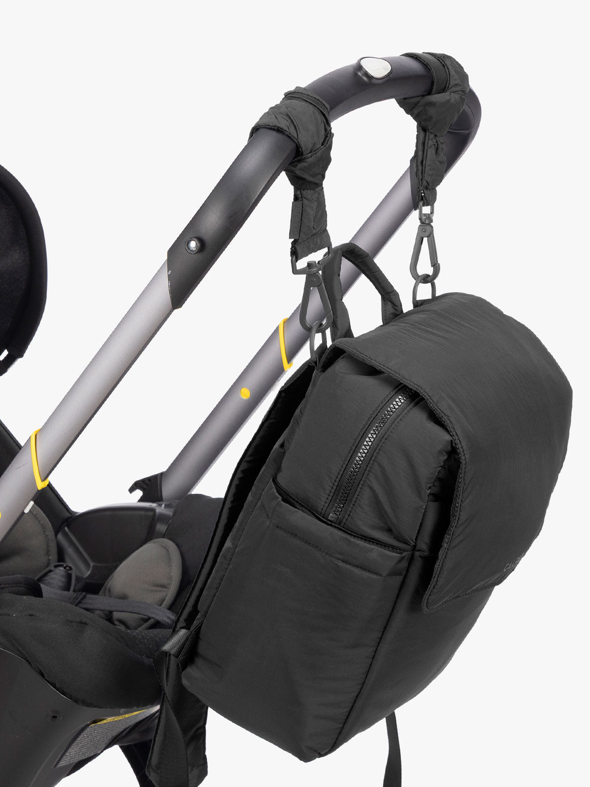 CALPAK Mini Diaper Backpack in Black strung on a stroller with stroller straps on a white background; BPC2402-BLACK