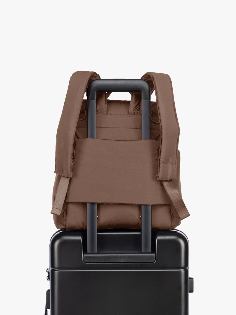 Luggage trolley sleeve of the CALPAK Mini Diaper Backpack in brown Hazelnut on a white background