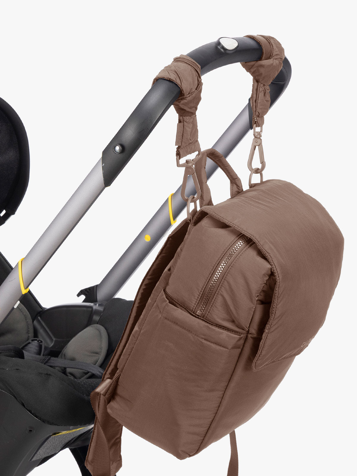 CALPAK Mini Diaper Backpack in brown Hazelnut hung on a stroller with straps on a white background; BPC2402-HAZELNUT
