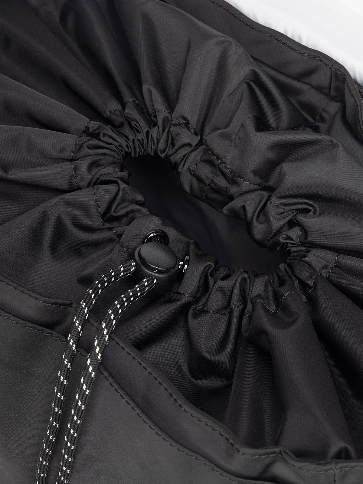 Close-up of a gray drawstring bag with a button closure of CALPAK Fit Gym Backpack in light purple Iris with white background; BPF2601-BLACK