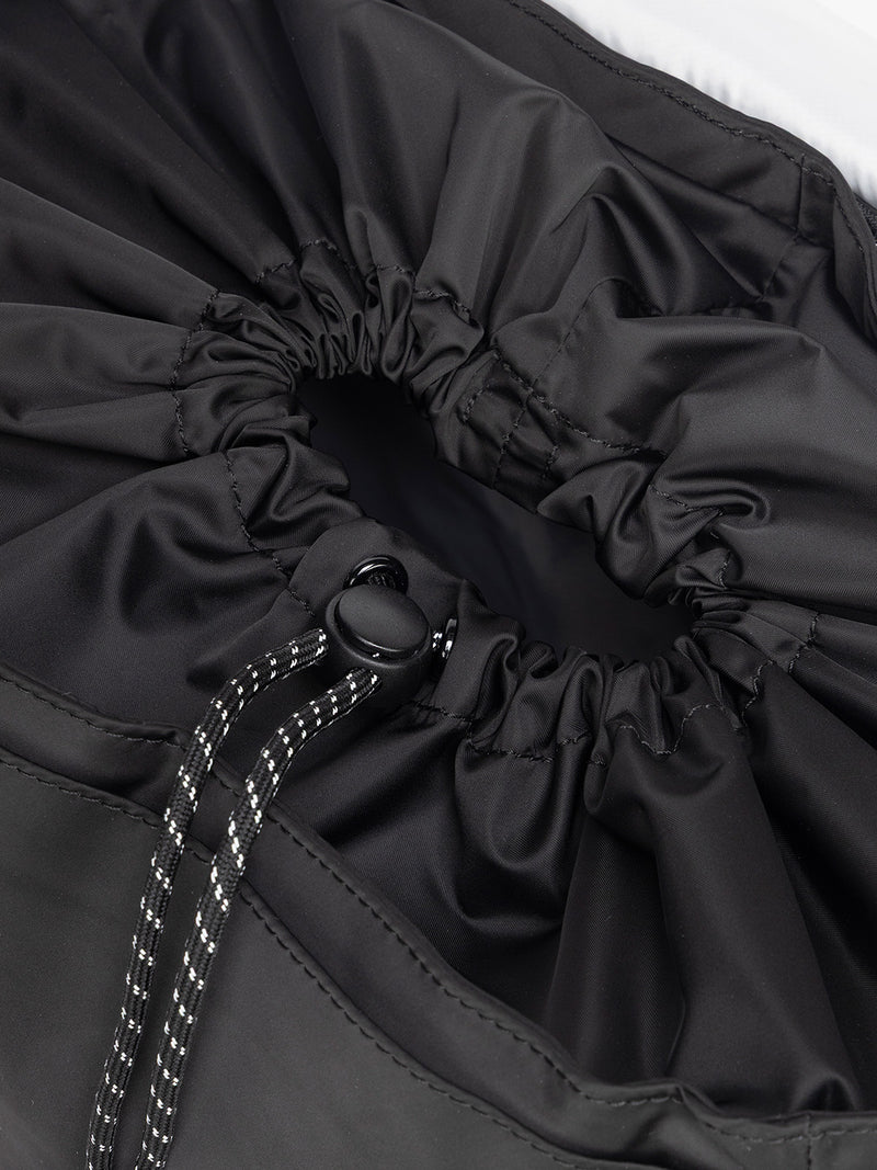 Close-up of a gray drawstring bag with a button closure of CALPAK Fit Gym Backpack in light purple Iris with white background