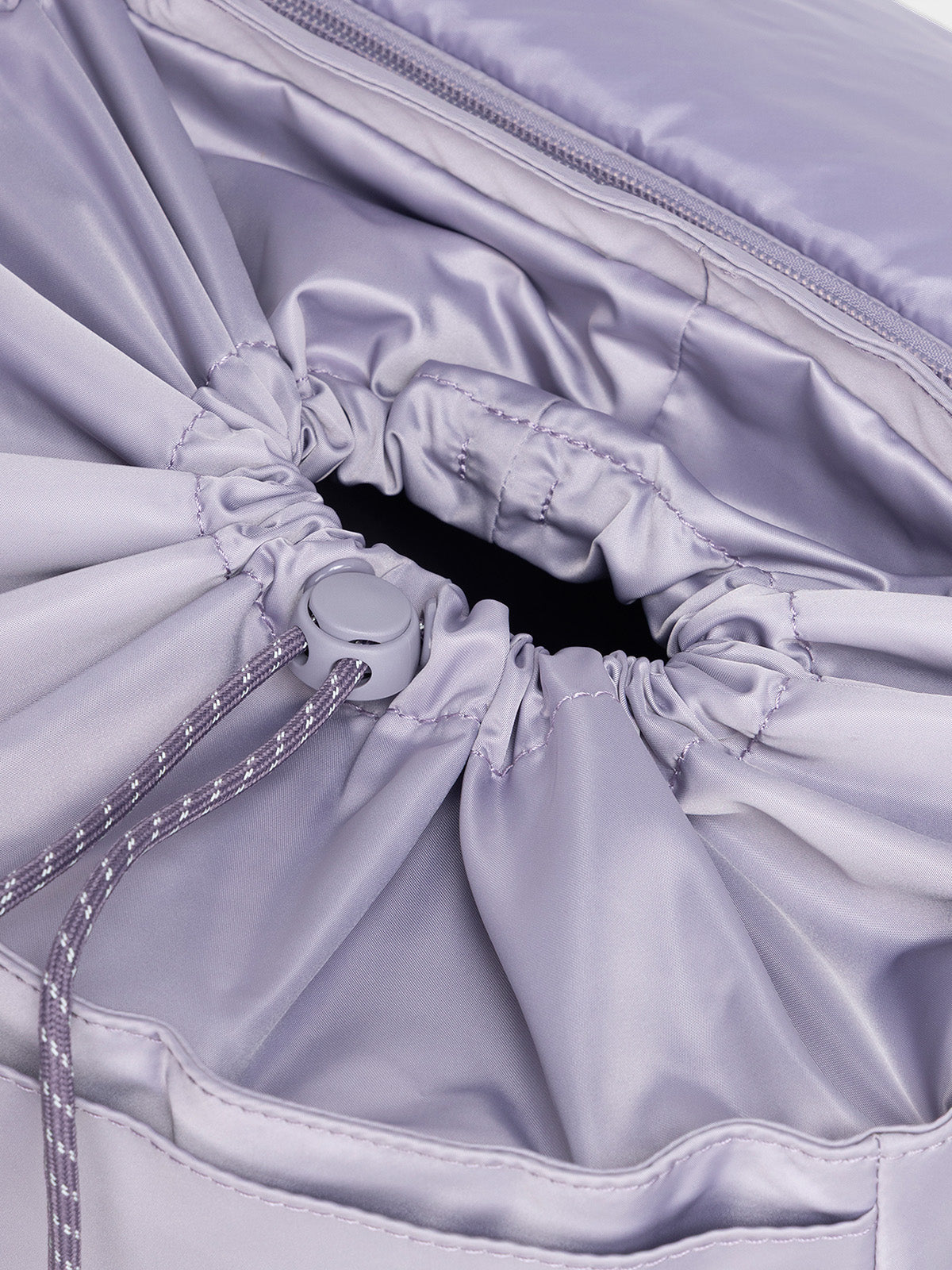 Model using drawstring closing feature of CALPAK Fit Gym Backpack in light purple Iris front view with white background; BPF2601-IRIS