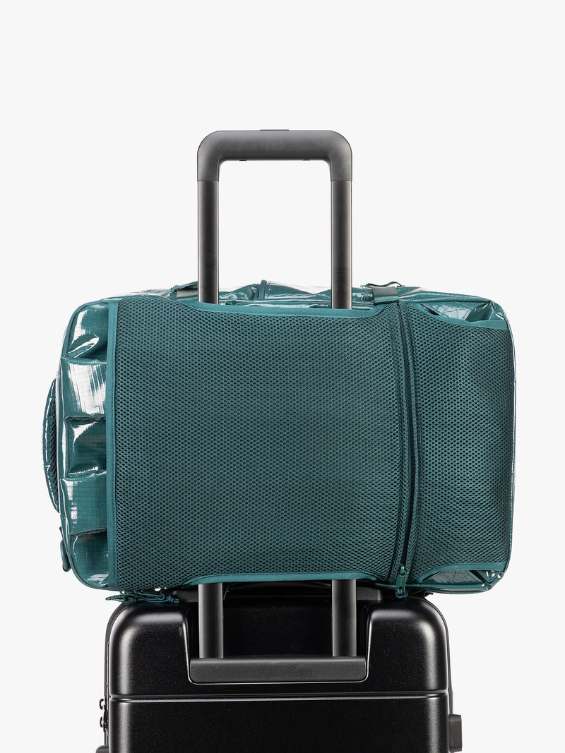 Backside trolley sleeve of CALPAK Terra 26L Laptop Backpack in dark blue green Kale with multiple pockets on a white background