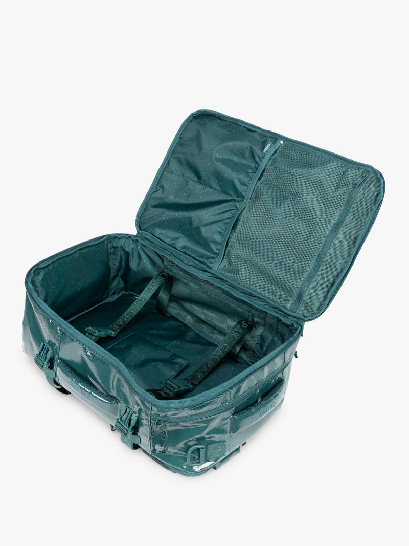 Opened CALPAK Terra 26L Laptop Backpack in dark blue green Kale with multiple pockets on a white background