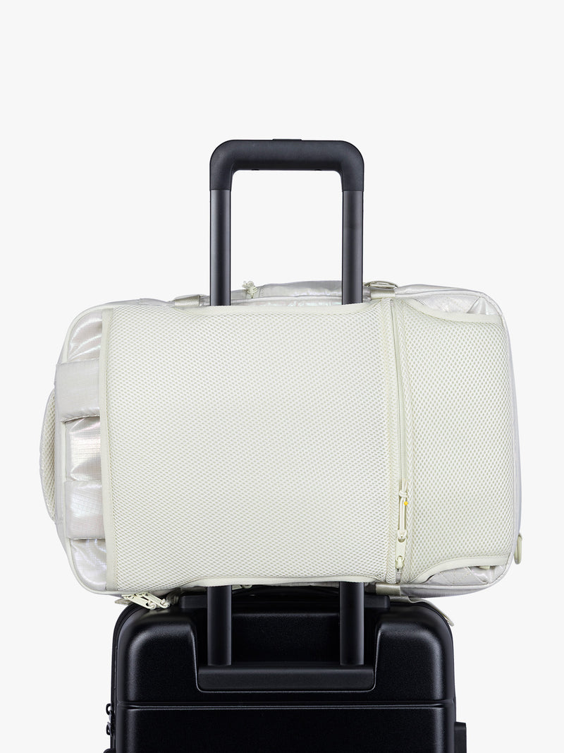 Luggage trolley sleeve of CALPAK Terra 26L Laptop Duffel Backpack with multiple pockets in shiny white Moonbeam on a white background