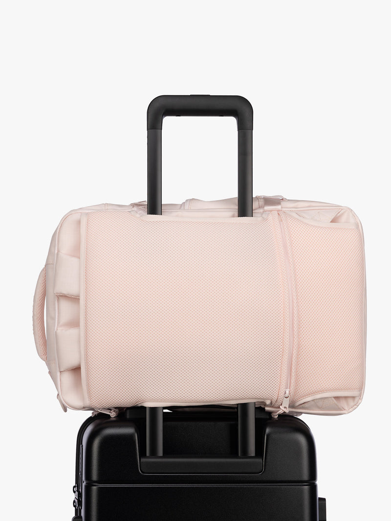 Luggage trolley sleeve of CALPAK Terra 26L Laptop Duffel Backpack with multiple pockets in light pink Shell Pink on a white background