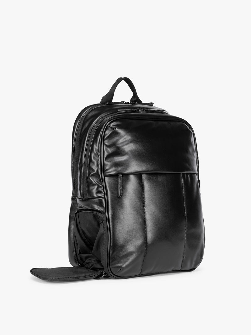 Side shoe compartment of Black CALPAK Luka 15 inch Laptop Backpack in vegan leather with a glossy finish, featuring a top carry handle, a main zippered compartment, and a front slip pocket, shown against a plain white background