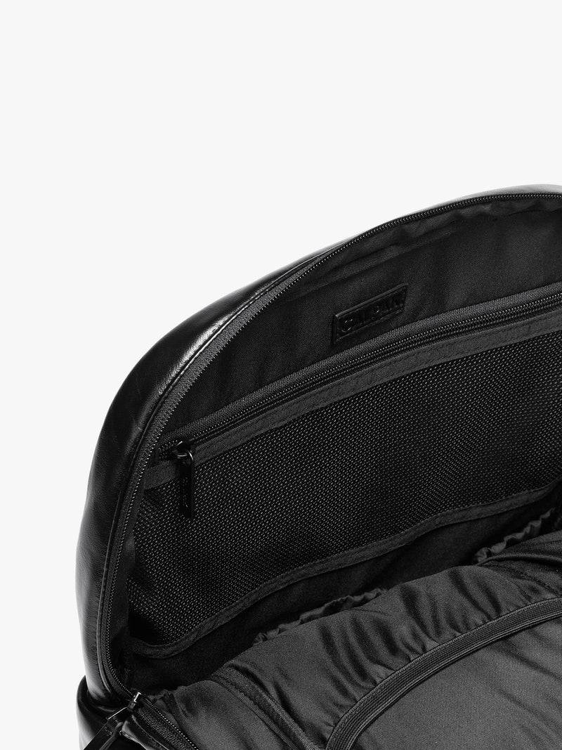 Inside zipper of CALPAK Luka 15 inch Laptop Backpack in vegan leather with a glossy finish, featuring a top carry handle, a main zippered compartment, and a front slip pocket, shown against a plain white background
