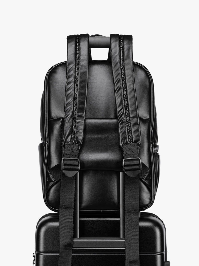Backside luggage trolley sleeve of CALPAK Luka 15 inch Laptop Backpack in vegan leather with a glossy finish, featuring a top carry handle, a main zippered compartment, and a front slip pocket, shown against a plain white background
