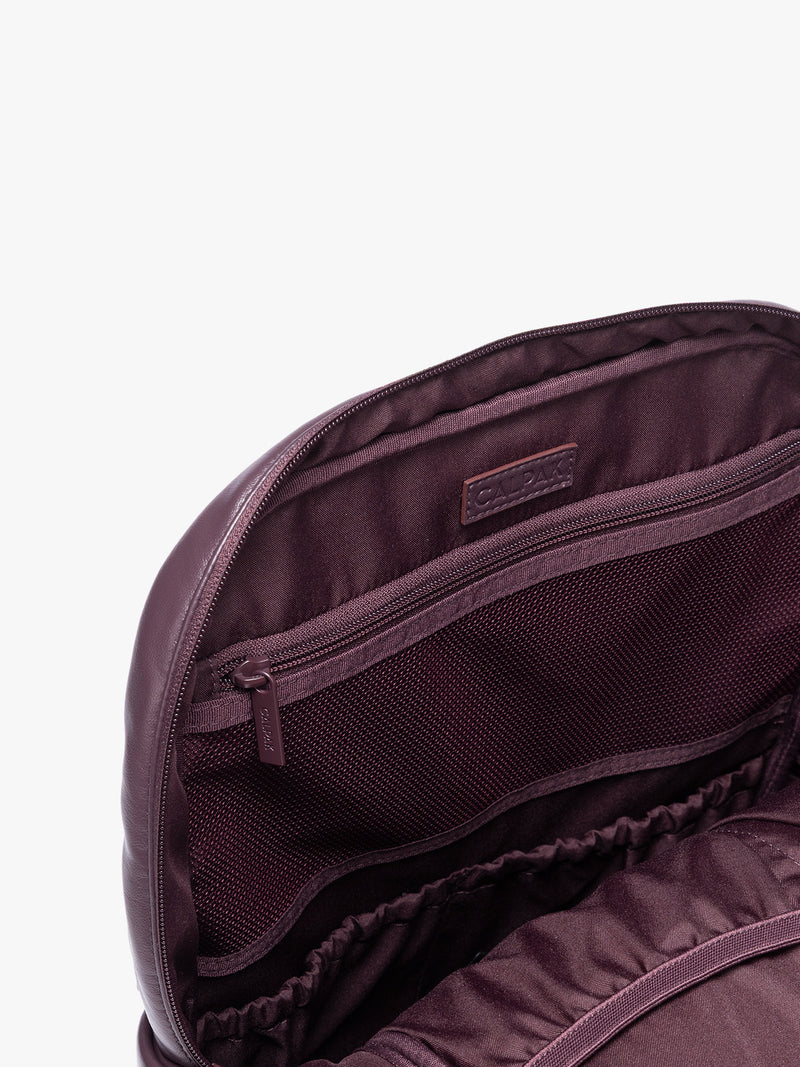 Inside zipper of CALPAK Dark Cherry Luka 15 inch Laptop Backpack in vegan leather with a glossy finish, featuring a top carry handle, a main zippered compartment, and a front slip pocket, shown against a plain white background