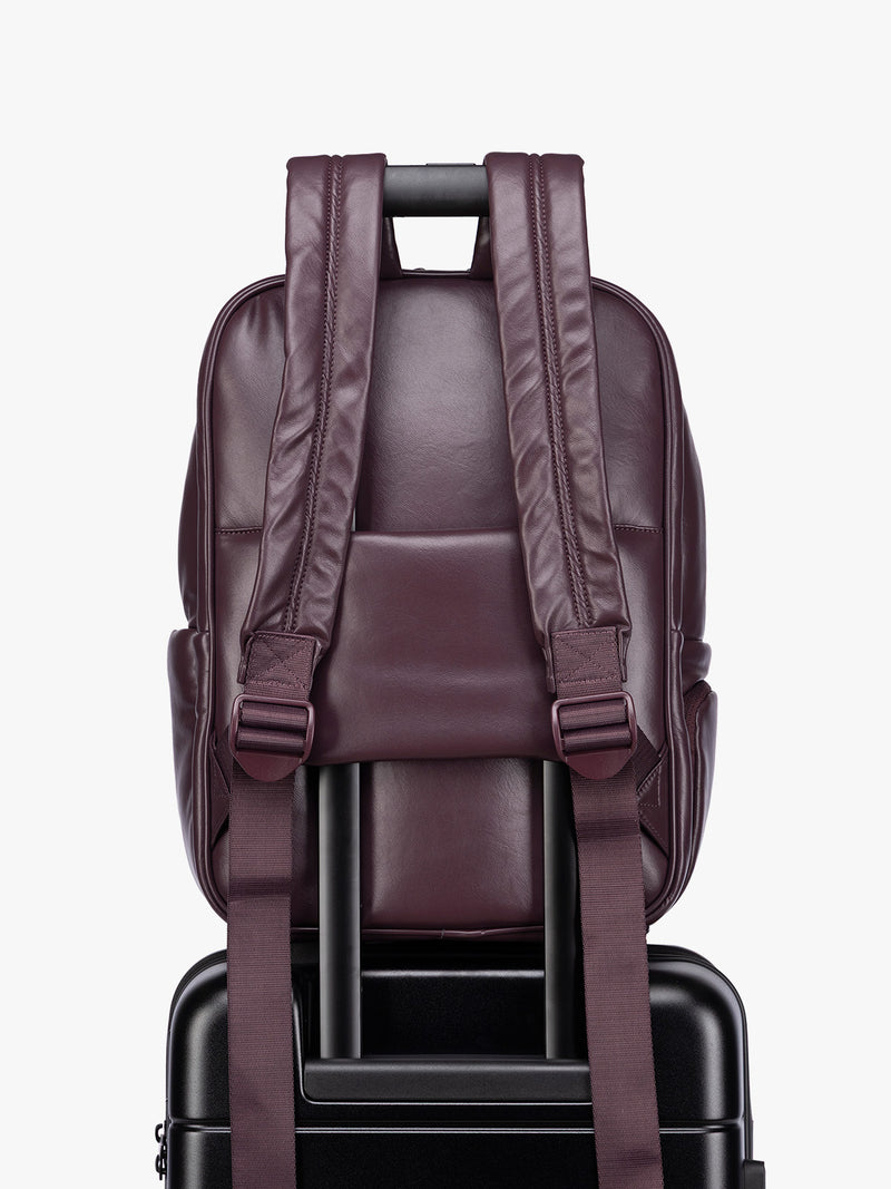 Back luggage trolley sleeve of CALPAK Dark Cherry Luka 15 inch Laptop Backpack in vegan leather with a glossy finish, featuring a top carry handle, a main zippered compartment, and a front slip pocket, shown against a plain white background