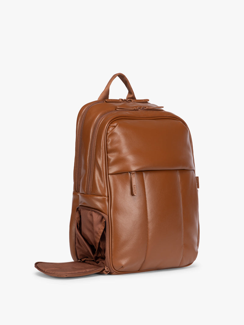 Side shoe compartment of CALPAK Honey Brown Luka 15 inch Laptop Backpack in vegan leather with a glossy finish, featuring a top carry handle, a main zippered compartment, and a front slip pocket, shown against a plain white background