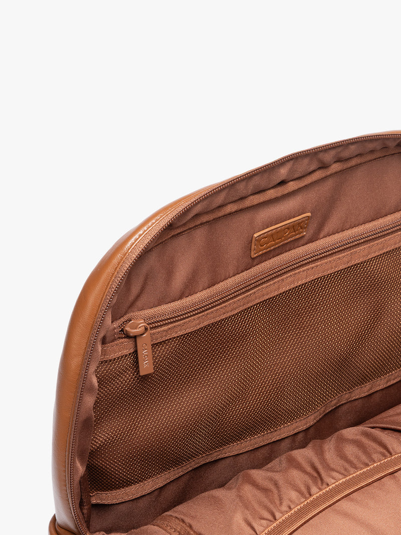 Inside zipper of CALPAK Honey Brown Luka 15 inch Laptop Backpack in vegan leather with a glossy finish, featuring a top carry handle, a main zippered compartment, and a front slip pocket, shown against a plain white background