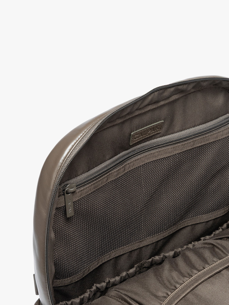 Closeup of zipper inside the CALPAK Mushroom brown Luka 15 inch Laptop Backpack in vegan leather with a glossy finish, featuring a top carry handle, a main zippered compartment, and a front slip pocket, shown against a plain white background