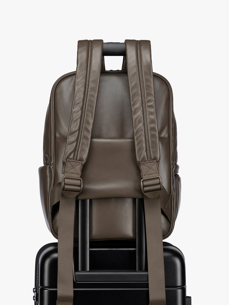Backside luggage trolley sleeve of CALPAK Mushroom brown Luka 15 inch Laptop Backpack in vegan leather with a glossy finish, featuring a top carry handle, a main zippered compartment, and a front slip pocket, shown against a plain white background