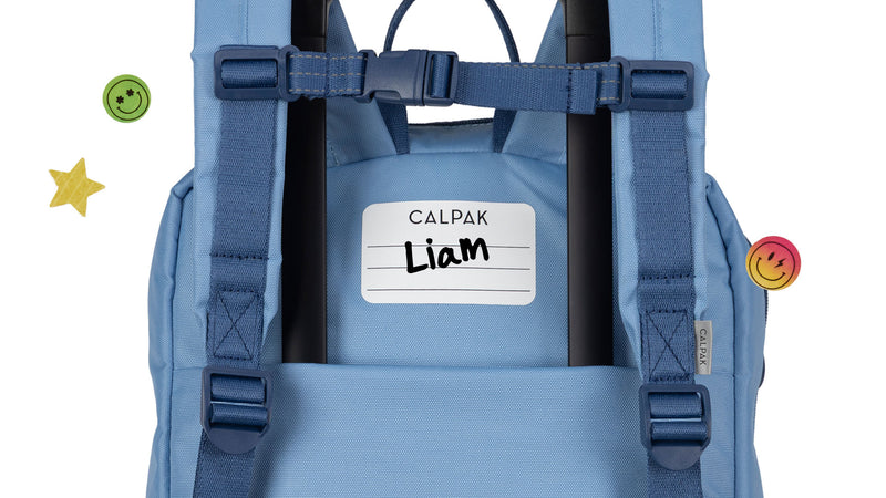 CALPAK Kids Backpack in Blue with white identification label on the back that reads name "Liam"