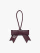 Burgundy Dark Cherry CALPAK Personalized Bow Bag Charm with a top loop, featuring a silver-tone metal ring and white embroidered initials 'SC' on one ribbon tail, set against a plain light gray background ; BWBC2601-DARK-CHERRY