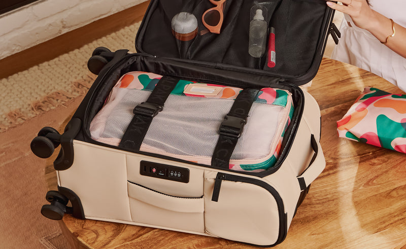 Interior shot of CALPAK Soft-Sided Carry-On Luggage with packing cube packed within secured by adjustable strap with buckle