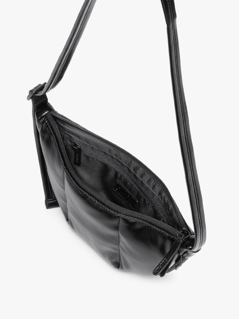 Top view with zipper opening of Black vegan leather Luka Crescent shoulder bag with a long thin strap, shown against a plain light gray background