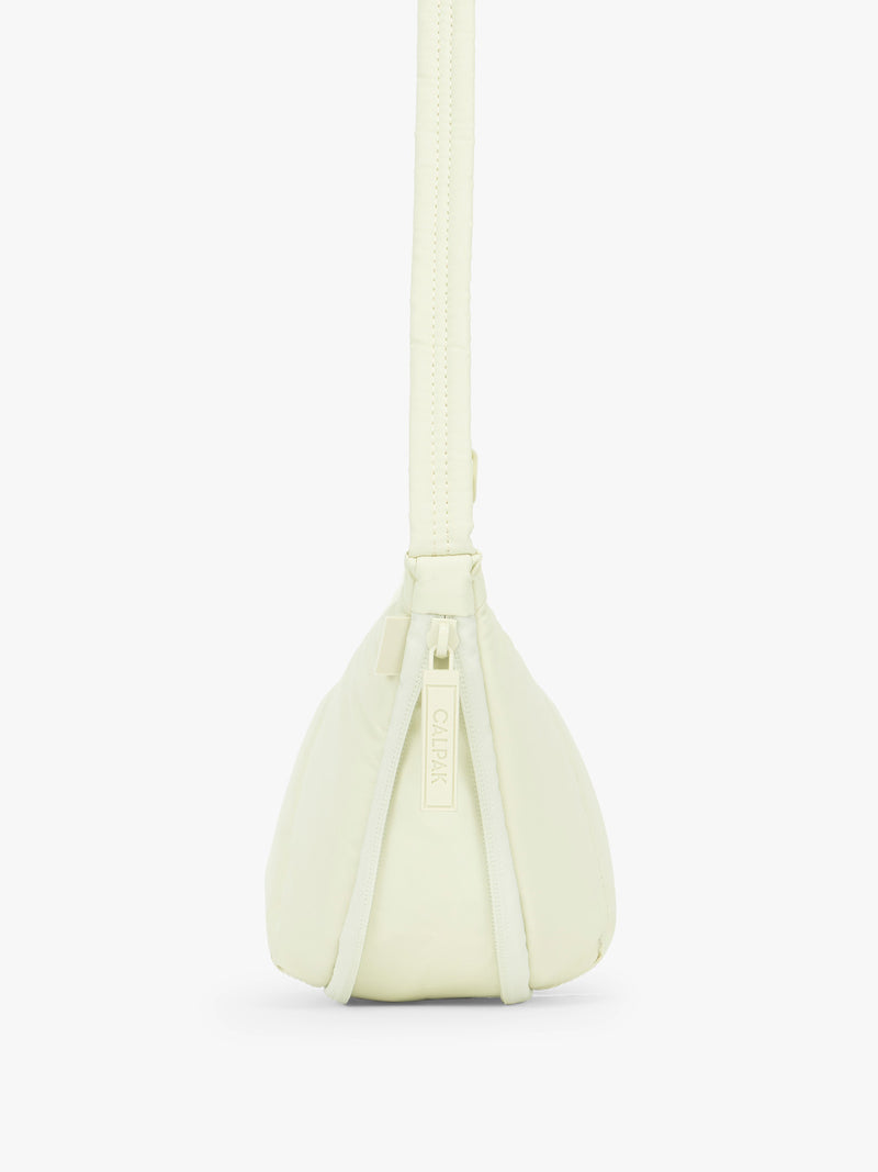 Side view showing expandable function of the CALPAK Luka Crescent Tote bag in light green Celadon with shoulder strap and bag is expandable up to 2" on a white background