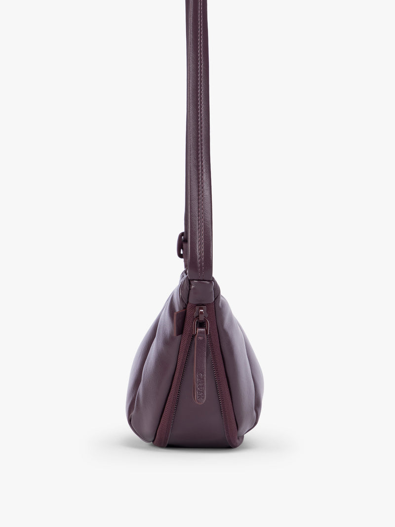 Side expandable zipper of Dark Cherry deep burgundy vegan leather Luka Crescent shoulder bag with a long thin strap, shown against a plain light gray background