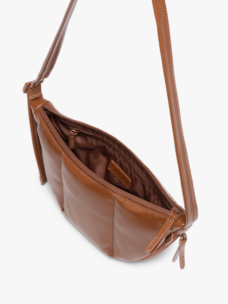 Top view with zipper opened of Honey Brown vegan leather Luka Crescent shoulder bag with a long thin strap, shown against a plain light gray background
