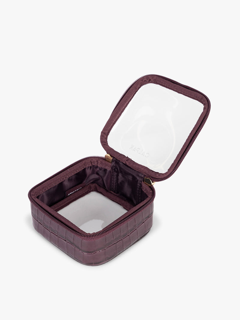 Opened CALPAK Tiny Clear Cosmetics Case that is a transparent pouch with a deep red Dark Cherry in crocodile-embossed