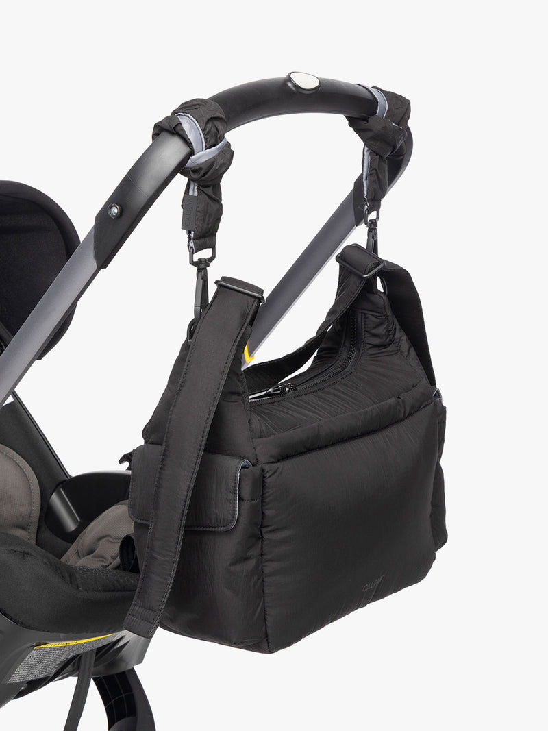CALPAK Crossbody Diaper Bag in Black strapped on stroller with Stroller Straps