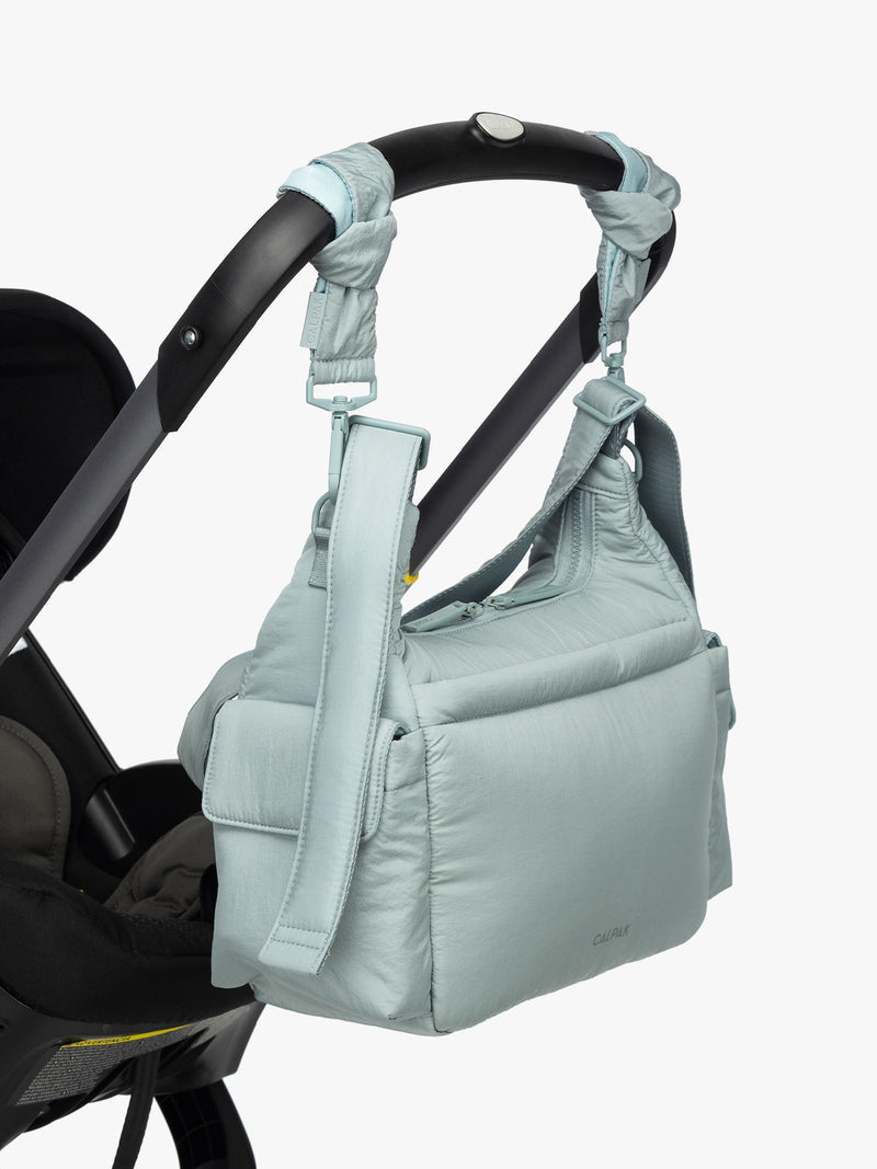 CALPAK Crossbody Diaper Bag in light blue Bluebell strapped on stroller with Stroller Straps
