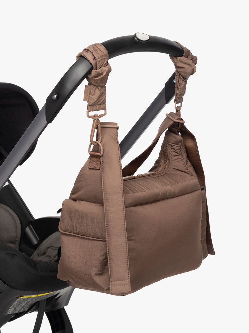 CALPAK Crossbody Diaper Bag in brown Hazelnut strapped on stroller with Stroller Straps