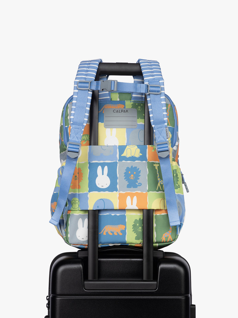 Back side with luggage trolley sleeve of CALPAK Kids Large Backpack with Miffy and blue colorful animal pattern on a white background